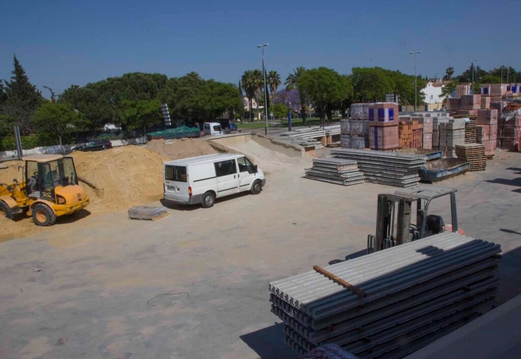 Explanada de Calería Los 9 con palés de ladrillos, viguetas y una carretilla elevadora